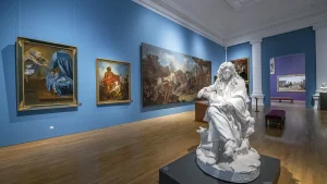 Mur bleu dans un musée, statue en pierre blanche, tableau dans un musée